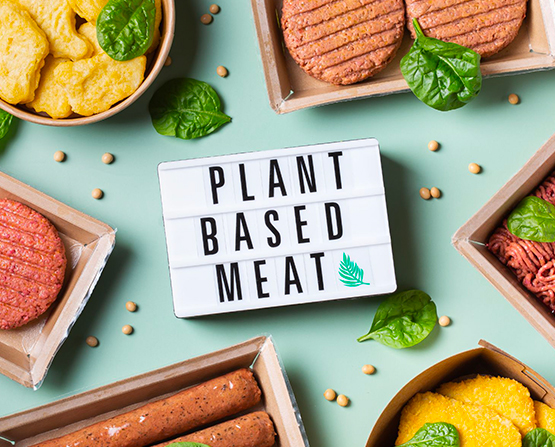 Une boite sur laquelle est inscrit le mot 'PLANT BASED MEAT' et entourer de produits alimentaires